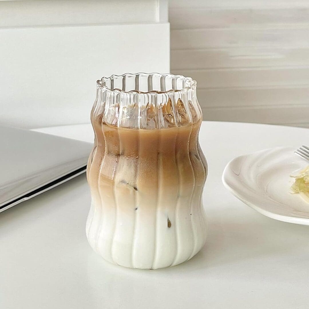 Glass of iced latte in ribbed glass.